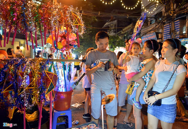 Một số gian hàng bán đồ chơi truyền thống được nhiều gia đình cho trẻ nhỏ lựa chọn. Trong ảnh, bé Bi được bố mẹ mua tặng đèn ông sao để dạo phố.
