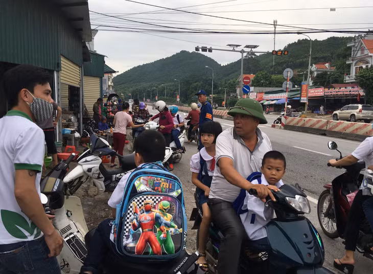 Người và phương tiện đưa đón con, đi chợ đỗ tràn xuống cả lòng đường.