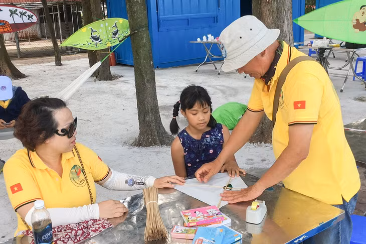 Du khách trải nghiệm làm diều truyền thống.