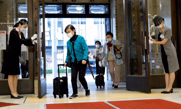 Nhân viên trung tâm thương mại Nihombashi Takashimaya đeo khẩu trang cúi chào khách tới tham quan. Ảnh: Reuters
