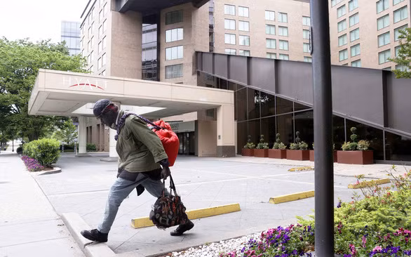 Một người vô gia cư đi qua khách sạn Hyatt ở Washington, Mỹ ngày 8/5, khi khách sạn này đang đóng cửa hoàn toàn vì COVID-19. Ảnh: Reuters