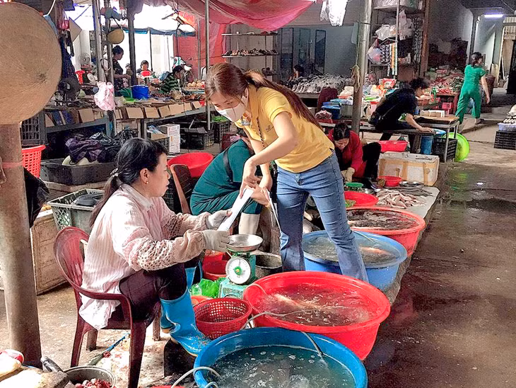 Nhân viên Đại lý BHXH huyện Tiên Yên tuyên truyền về BHYT cho các hộ kinh doanh tại chợ Đông Ngũ (Tiên Yên) vào đầu tháng 5/2020. 