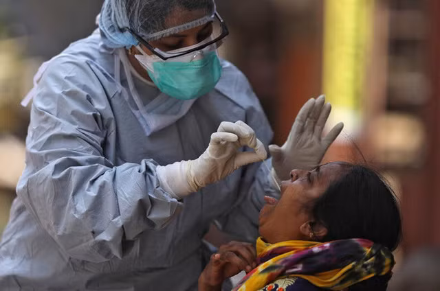 Bác sĩ Ấn Độ lấy mẫu xét nghiệm COVID-19 cho một người dân ở thành phố Mumbai. Ảnh: Reuters