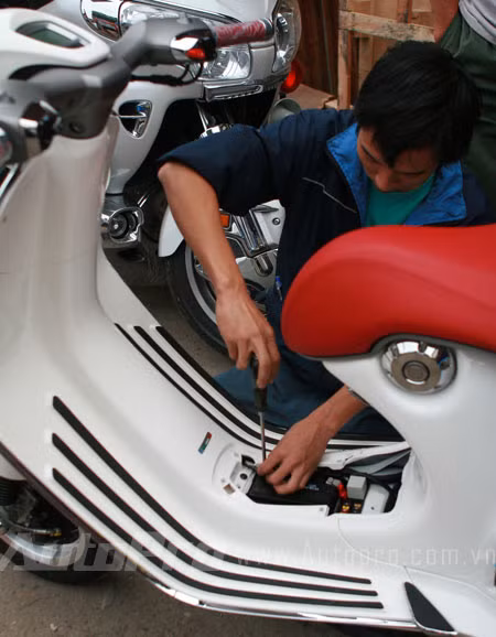Kỹ thuật viên đang lắp bình ắc-quy để nổ máy xe.