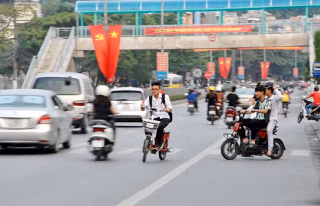 Học sinh Trường THPT Hòn Gai đi xe đạp điện không đội mũ bảo hiểm, đi ngược chiều ngay trước cổng trường.
