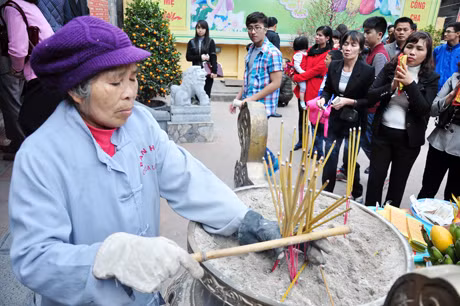 Những người làm công quả thu dọn chân hương đề phòng hoả hoạn.