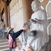 Nhiều người cho rằng phải dúi đồng tiền vào tận tay tượng thì “ngài” mới chứng. (Ảnh minh họa)