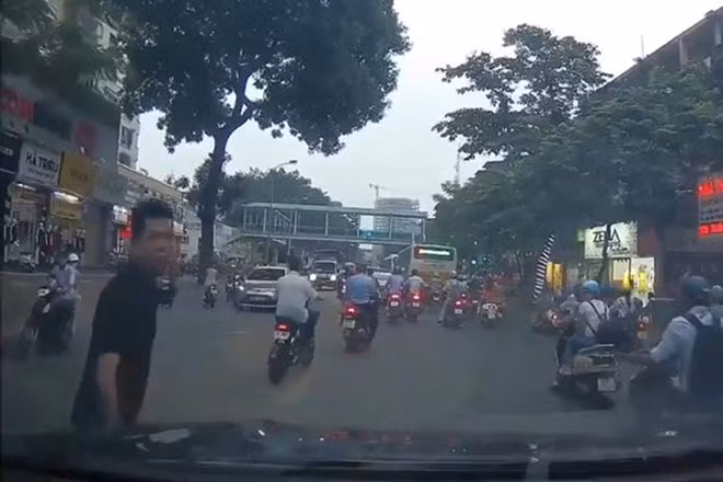 Ngang nhiên đứng trước đầu xe đang di chuyển (Ảnh: Cắt từ Clip)