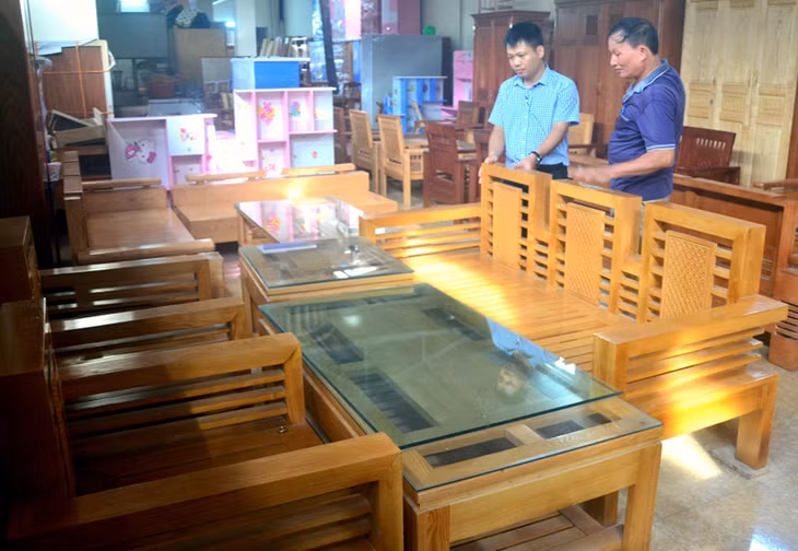 Thương binh Nguyễn Quang Văn giới thiệu sản phẩm nội thất gỗ cho khách hàng.