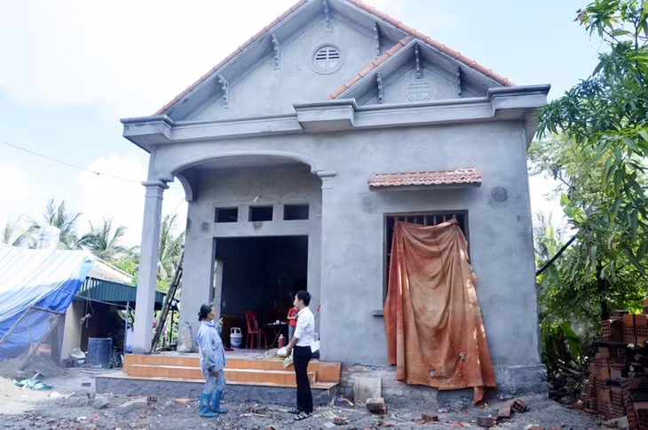 Vợ thương binh Lê Văn Hùng, khu phố 11, phường Hà An, TX Quảng Yên bên ngôi nhà được xây mới từ chính sách hỗ trợ nhà ở cho NCC.