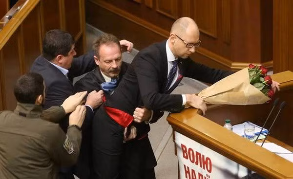 Ông Oleg Barna tặng một bó hoa rồi tìm cách bế Thủ tướng Arseny Yatsenyuk khỏi bục phát biểu trước Quốc hội. (Nguồn: kyivpost.com)