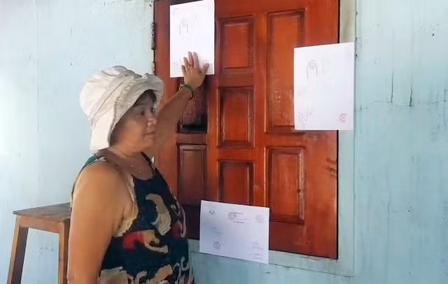 Bà Vương chỉ nơi nghi là có kẻ xấu dùng búa đập vỡ cửa sổ để đưa xăng vào trong nhà phóng hỏa.