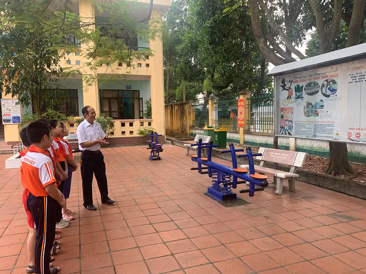 Các em học sinh Trường Tiểu học Lý Thường Kiệt, TP Uông Bí đang nghe các CCB truyên truyền Luật Giao thông. 