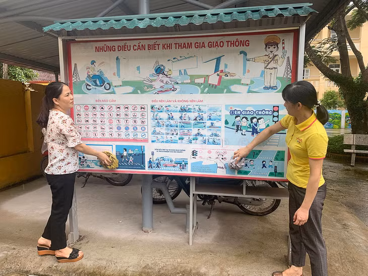 Các cô giáo Trường Phổ thông Dân tộc Bán trú TH&THCS xã Hà Lâu, huyện Tiên Yên lau bàng tin ATGT của nhà trường để tuyên truyền cho các em học sinh châp hành Luật Giao thông.