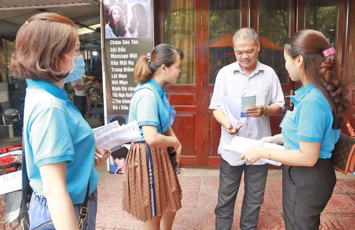 Nhân viên BHXH huyện Tiên Yên và Bưu điện huyện Tiên Yên vận động người dân trên địa bàn huyện tham gia BHXH tự nguyện.