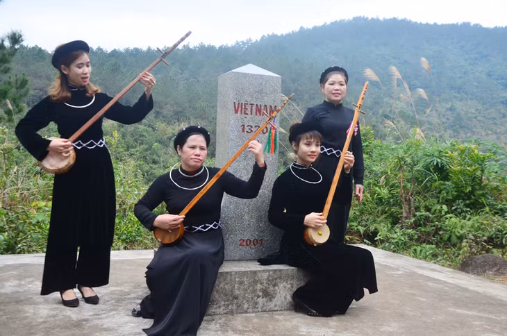Phụ nữ Tày huyện Bình Liêu đàn tính hát then bên cột mốc biên giới. Ảnh: Phạm Học (Chụp tháng 11/2019)