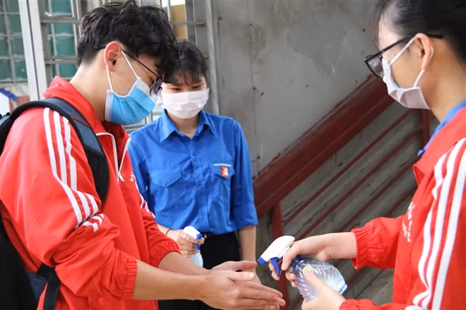 Sinh viên đại học xịt tay khử khuẩn, đeo khẩu trang.