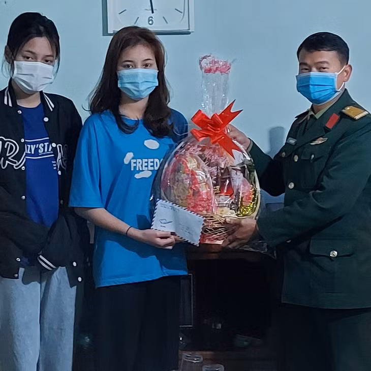 Thiếu tá Phạm Văn Kiên, Chính trị viên Tiểu đoàn Bộ đội đảo Cô Tô tặng quà Tết của đơn vị cho 2 chị em Nguyễn Thị Huyền, Nguyễn Thị Miên, mồ côi cha mẹ ở thôn Hồng Hải, xã Đồng Tiến (Cô Tô).