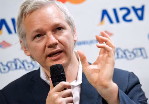 Ông Assange nói trong một cuộc họp báo tại London hôm qua, với phông nền phía sau là biểu trưng in ngược của các tổ chức tài chính và tín dụng nổi tiếng. Ảnh: AFP