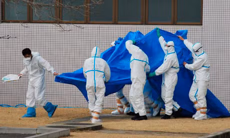 Các công nhân trong nhà máy điện hạt nhân Fukushima I đưa một đồng nghiệp ra ngoài nhà máy sau khi người này phơi nhiễm phóng xạ hồi tháng 4. Ảnh: AP.