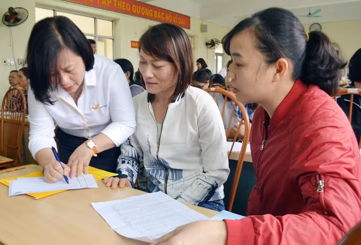 Cán bộ cơ quan Bưu điện TX Quảng Yên trực tiếp hướng dẫn người dân kê khai đăng ký tham gia BHXH tự nguyện tại hội 
