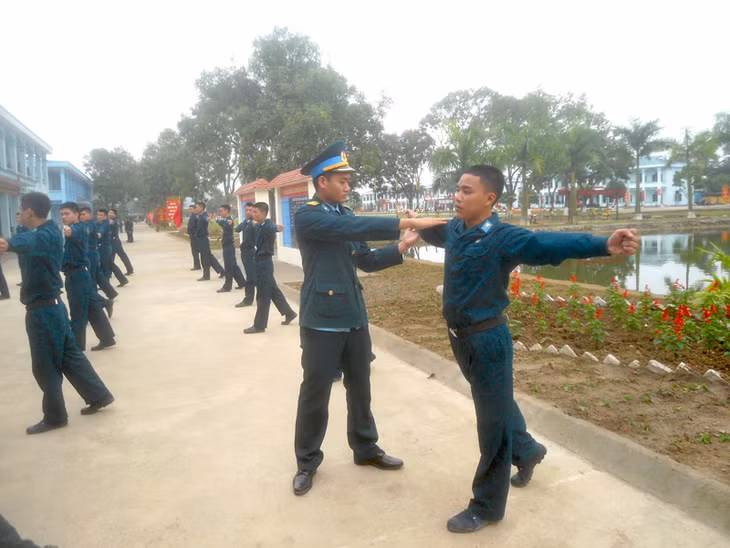 Chiến sỹ Hoàng Tuấn Anh (phải) được cán bộ trực tiếp sửa động tác thể dục sáng