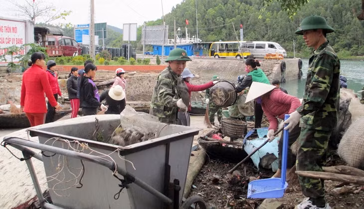 Các chiến sĩ Đồn Biên phòng Ngọc Vừng cùng nhân dân dọn vệ sinh môi trường tại khu vực cảng tàu thôn Ngọc Nam, xã Ngọc Vừng. 