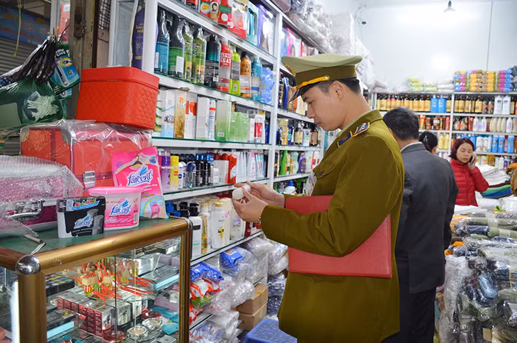 Cán bộ Đội QLTT số 5 kiểm tra việc niêm yết giá của một của hàng kinh doanh tại Chợ Hạ Long 1