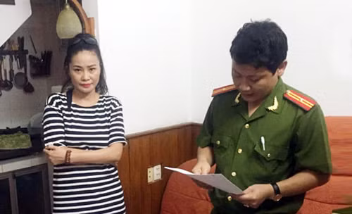 Một phụ nữ bị cáo buộc tham gia "tập đoàn Thánh bóc" nghe cảnh sát tống đạt lệnh bắt. Ảnh: Công an nhân dân