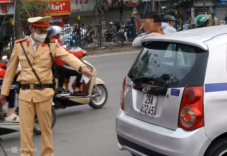 Cảnh sát dừng chiếc taxi dùng băng dính đen để ’biến’ số 9 thành số 0. Ảnh: Bá Đô