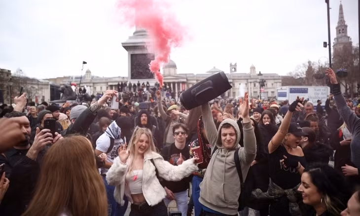 Người dân nhảy nhót, đốt pháo sáng khi biểu tình chống phong tỏa ở London, Anh, hôm 20/3. Ảnh: Reuters.