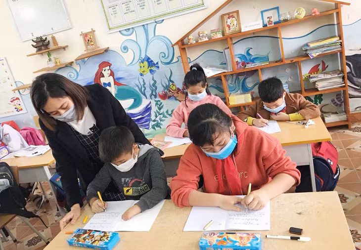 Cô giáo Nguyễn Thị Vân Anh hướng dẫn 2 em Trịnh Quốc Trường, Phạm Thị Ngân Hà, khuyết tật vận động, Trường Tiểu học Nguyễn Bình (TX Đông Triều), hoàn thành bài tập. (Ảnh do nhà trường cung cấp)