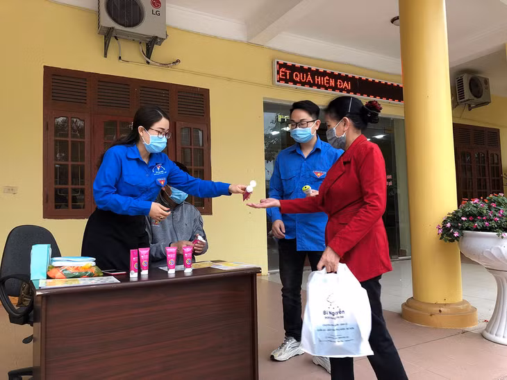 Chi Mai Việt Hồng (bên trái) đang hướng dẫn người dân sử dụng nước sát khuẩn phòng chống dịch Covid-19. 