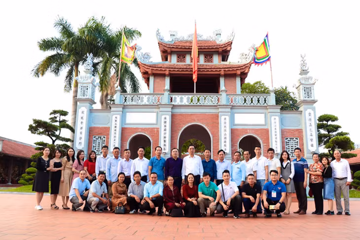 Du khách chụp ảnh lưu niệm cùng các thuyết minh viên tại Di tích Quốc gia Đền Xã Tắc. (Ảnh chụp năm 2020).