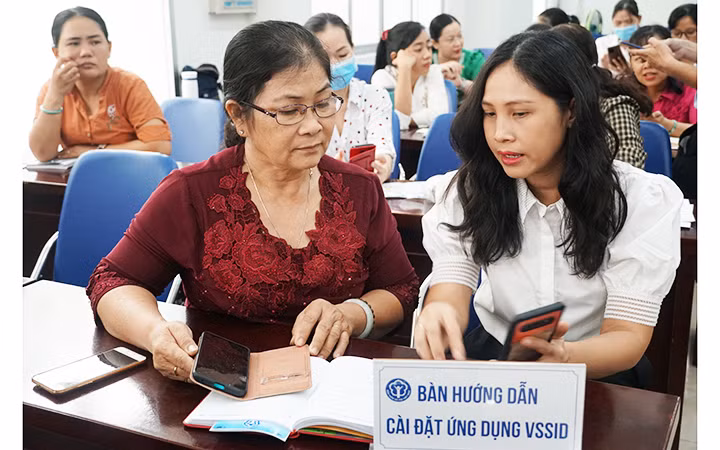 Cán bộ BHXH thành phố Hồ Chí Minh tư vấn, hướng dẫn người dân cài đặt và sử dụng ứng dụng VssID. Ảnh: TRUNG TÂM
