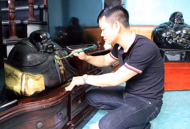 Anh Nguyễn Chí Linh thực hiện thao tác dát vàng lên tác phẩm điêu khắc tượng Phật Di Lặc.