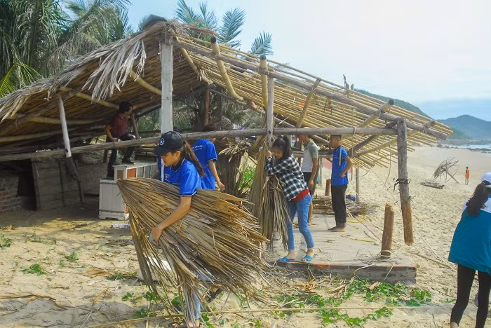 Đoàn viên, thanh niên hỗ trợ các hộ kinh doanh tháo dỡ lều kinh doanh trên bãi biển Quan Lạn.