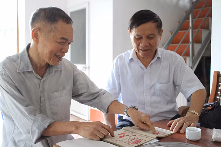 Ông Tiến (bên trái) chia sẻ tri thức dân gian trong sách chữ Nôm với cán bộ Hội Văn nghệ Dân gian Quảng Ninh.