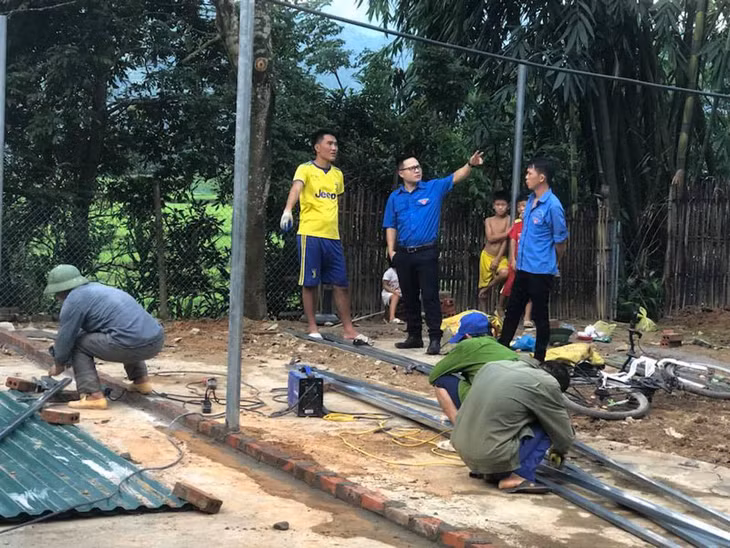 Anh Dũng (áo xanh, ở giữa) hướng dẫn thanh niên thôn Bản Chuồng, xã Lục Hồn xây dựng chuồng trại nuôi gà ta (Ảnh do nhân vật cung cấp)