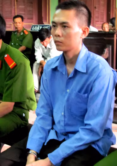 Hải trong giờ nghị án tại tòa hôm nay. Phía sau, người cha ngồi trầm tư vẻ đau khổ vì bị con trai đổ tội . Ảnh: Hải Duyên.
