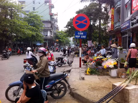Mặc dù có biển cấm nhưng nhiều người vẫn ngang nhiên họp chợ gây mất ATGT.