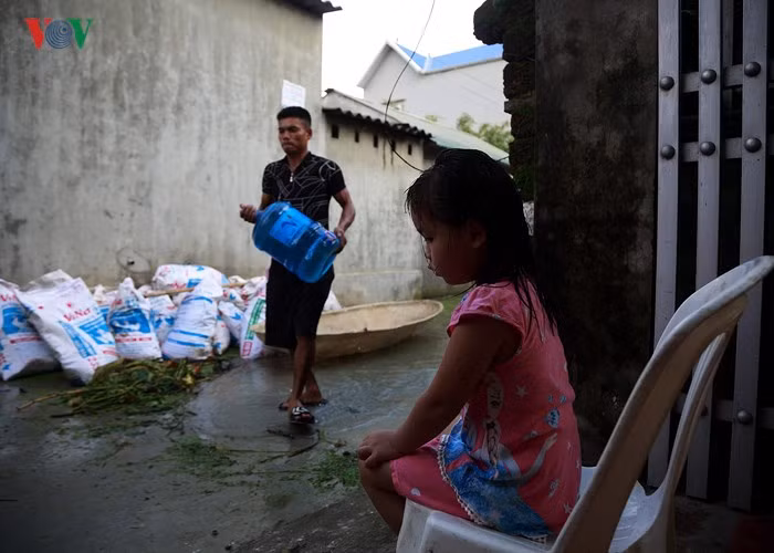  Những trẻ nhỏ tại vùng ngập không còn chỗ chơi bởi đâu đâu cũng là nước. Trong ảnh: Một em nhỏ ngồi trước cửa nhà "may mắn" có nền cao hơn những nơi khác chờ mẹ nhận tiếp tế ở đầu thôn.