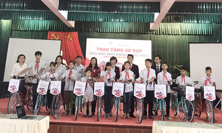 Đại diện Công ty BHNT Prudential Việt Nam và Hội CTĐ Quảng Ninh trao xe đạp cho các học sinh.