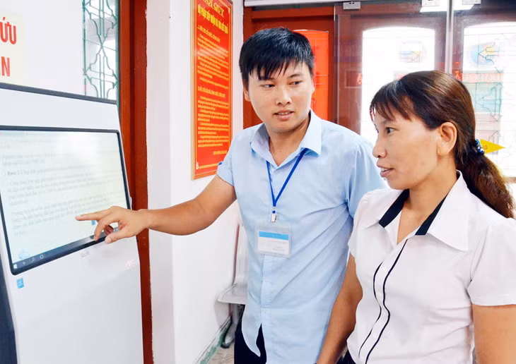 Cán bộ Bộ phận tiếp nhận và trả kết quả hiện đại phường Xuân Sơn (TX Đông Triều) hướng dẫn người dân tra cứu thủ tục hành chính bằng hệ thống tra cứu tự động.