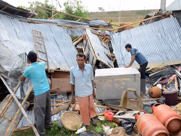 Người dân Ấn Độ dọn dẹp nhà cửa sau khi bão tràn qua làng Gazole ngày 22/4. (AFP/TTXVN)