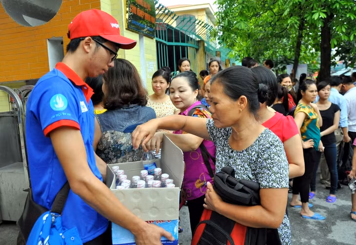 Tình nguyện viên phát nước miễn phí cho phụ huynh thí sinh bên ngoài khu vực thi tại Điểm thi Trường ĐH Công nghiệp Quảng Ninh.