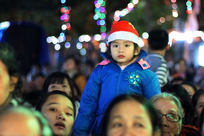 Dòng người đổ về nhà thờ Chính tòa mỗi lúc một đông. Bé gái trên vai người lớn tò mò trước khung cảnh lung linh của đêm lễ. 