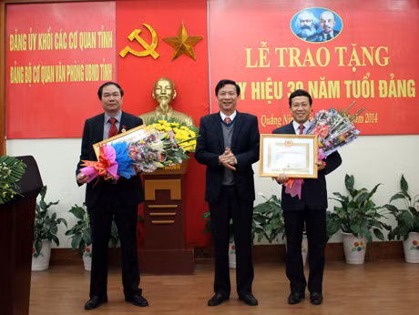 Đồng chí Nguyễn Văn Đọc, Chủ tịch UBND tỉnh tặng hoa chúc mừng các đồng chí nhận Huy hiệu 30 năm tuổi Đảng.