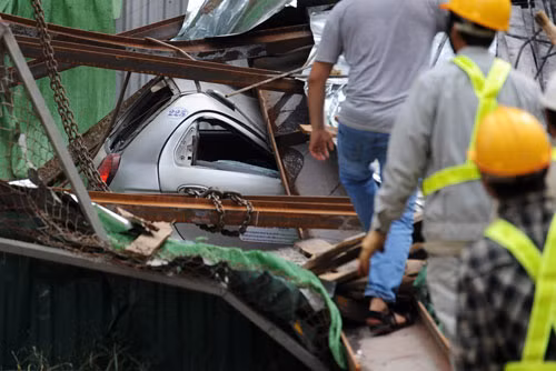 Chiếc taxi bị kẹt trong đống đổ nát. Theo các nhân chứng, các thanh chống đổ xuống trước, chắn ngang đường nên lái xe và hành khách có đủ thời gian thoát ra ngoài trước khi dàn giáo sụp xuống. Ảnh: Quý Đoàn.