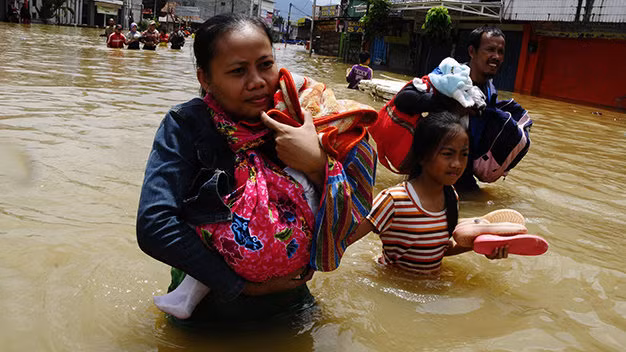 Người dân ôm đồ lội nước lụt đi sơ tán ở Tây Java, Indonesia - Ảnh: Reuters